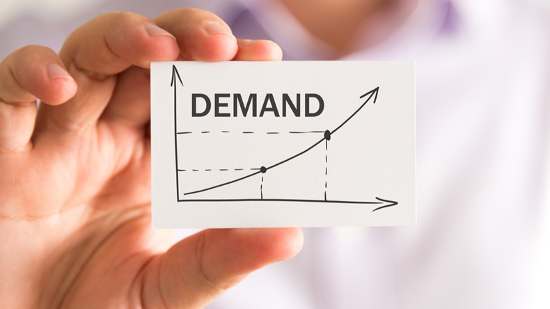 Closeup on businessman holding a card with DEMAND rising arrow and chart, business concept image with soft focus background