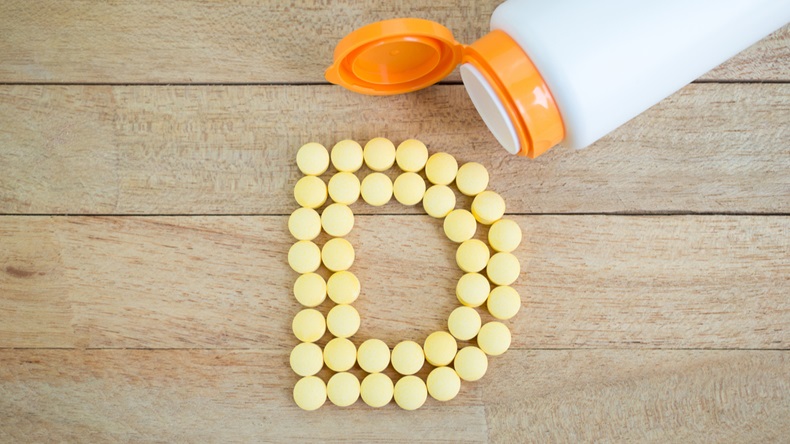 Yellow pills forming shape to D alphabet on wood background 