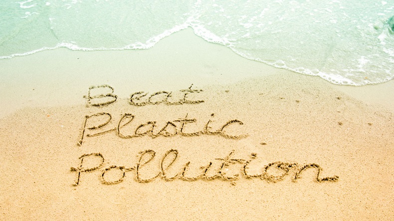 The word Beat Plastic Pollution, a campaign for the World Environment Day 2018, hand written on sandy beach background.
