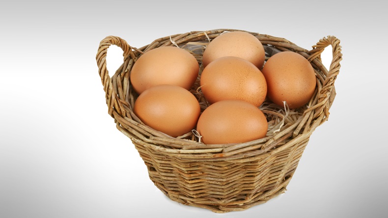 Wicker basket with six brown eggs. Isolated on white. Clipping path included.